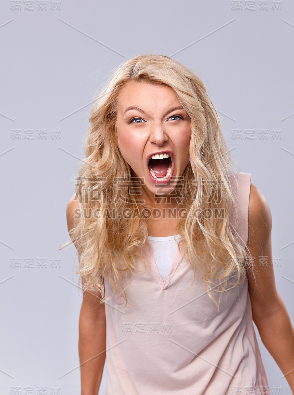 年轻情绪化的女人，孤立在灰色背景下