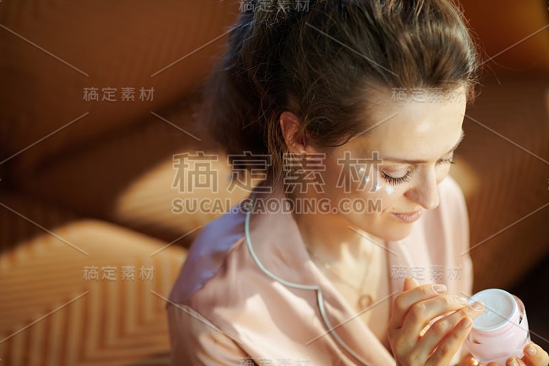 优雅的家庭主妇，用粉红色的化妆瓶敷眼霜