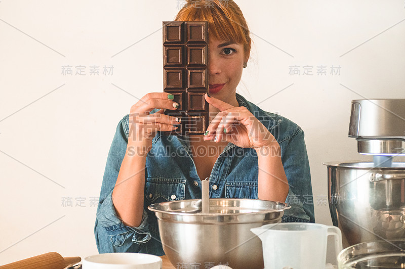 糖果红发女孩拿着巧克力，遮住了脸。概念配料烹饪面粉产品或甜点