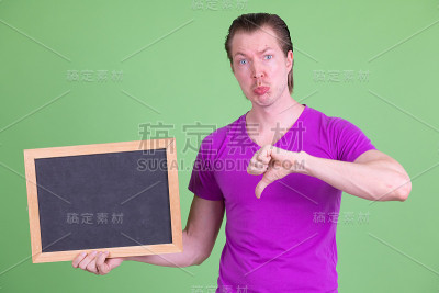 悲伤的年轻人的肖像拿着黑板和拇指向下