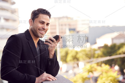 商人站在办公大楼外用手机，背景是城市天际线