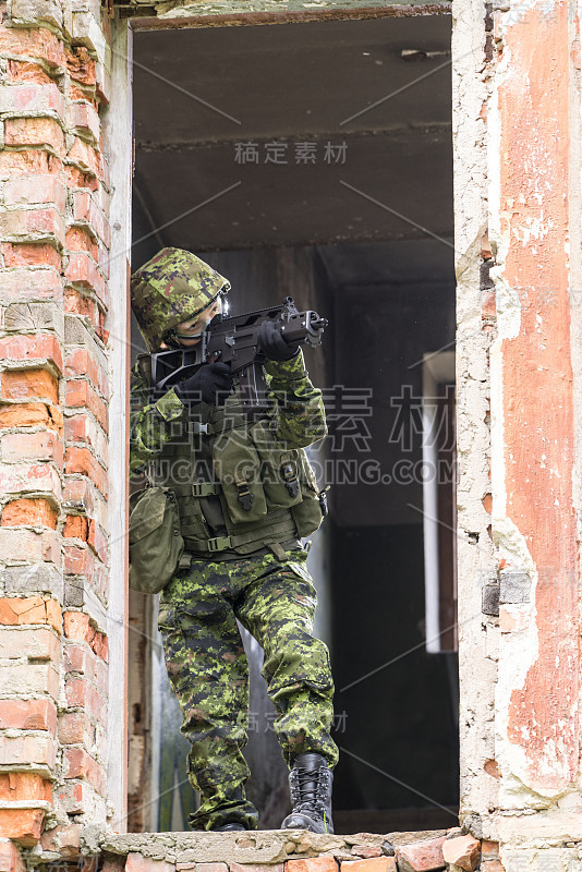 身着迷彩服的武装女子的肖像。年轻的女兵用枪观察。儿童兵与枪在战争壁炉，房子废墟的背景。军民观念，军民