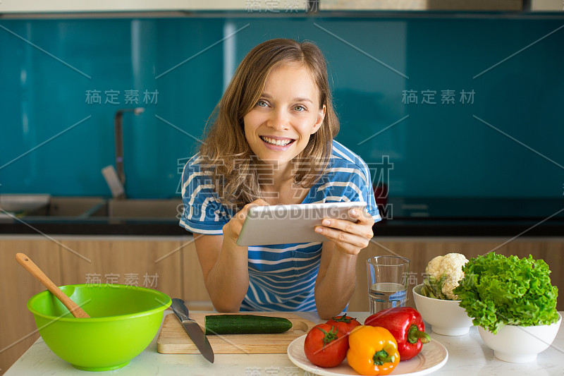 微笑的女人正在查看食谱和做沙拉