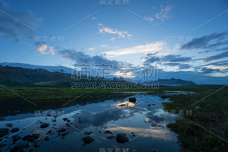 冰岛——黎明时分，白雪覆盖的山脉和冰川倒映在静静的水面上