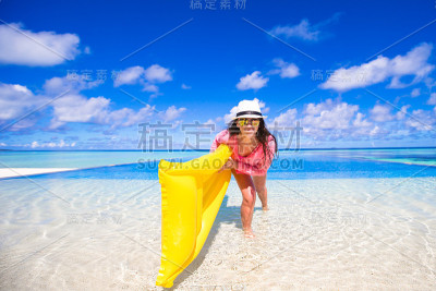 年轻快乐的女人放松与充气床垫在热带度假