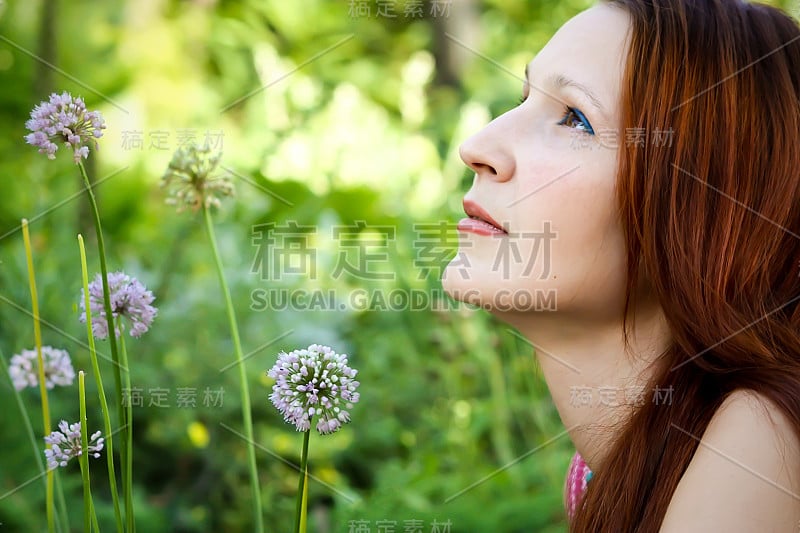 一个漂亮女孩浪漫地坐在美丽的花旁边的肖像