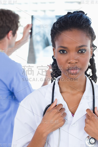 一名医生在看x光照片，而他的同事正在摆姿势