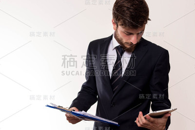 拿着剪贴板看平板电脑的商人