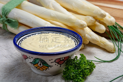 一束新鲜的生白芦笋和荷兰酱放在碗里