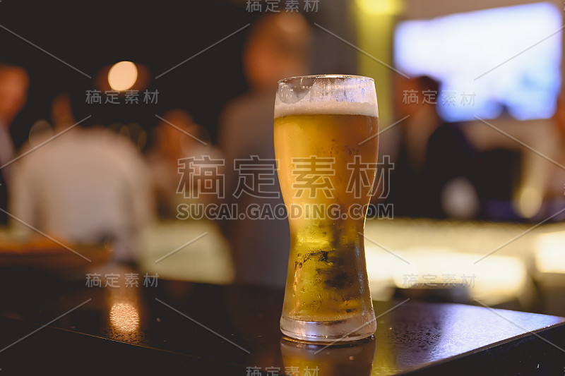 一杯啤酒在餐厅的空中吧台上投下了阴影。冰啤酒，下班后出去玩再好不过了。啤酒，闲逛，放松，餐厅，晚餐的