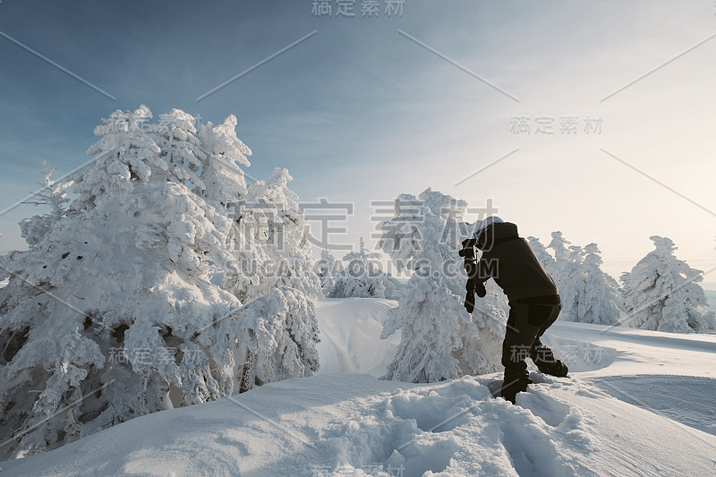 摄影师女性滑雪板拍照的美丽的冬季风景日落