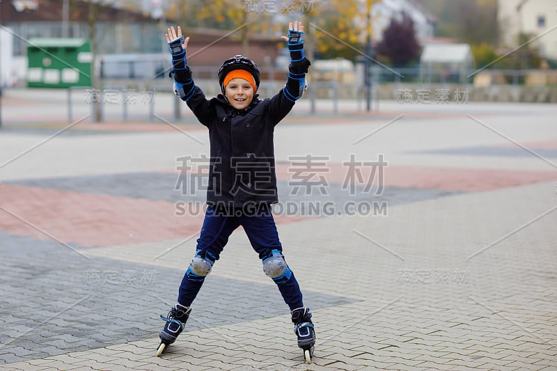 可爱的小男孩在城里滑旱冰。快乐健康的孩子穿着保护安全的衣服滑旱冰。积极的学生使运动和学习滑冰直排轮滑