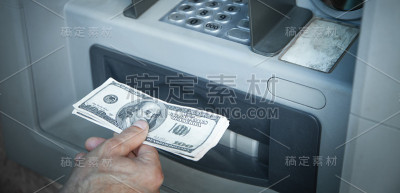 手里拿着从ATM机取款的美元。