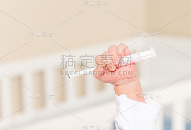 小婴儿用手抱着医用注射器