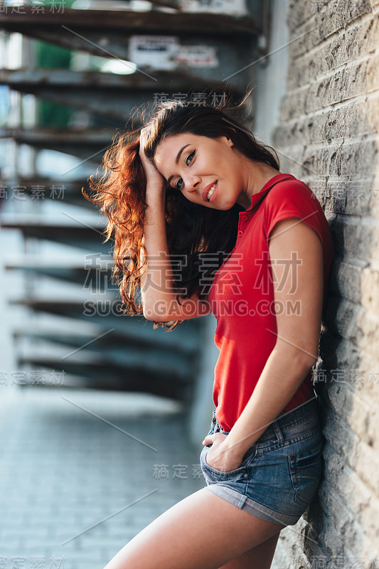 夏天的户外肖像年轻漂亮的女孩在城市日落摆姿势