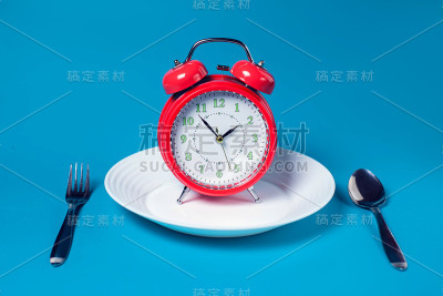 闹钟在白色板上的彩色背景。保健和食品概念