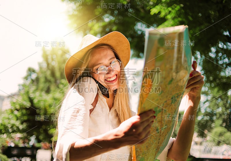 旅游理念，旅游新城。戴着毡帽和眼镜的美女游客看着城市地图和打电话。