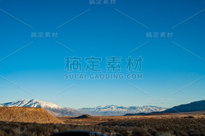 沙漠山谷与棕色的山丘和雪山山脉与蓝天