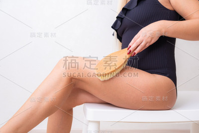 女性腿部用瘦身按摩刷。身体护理和美容理念