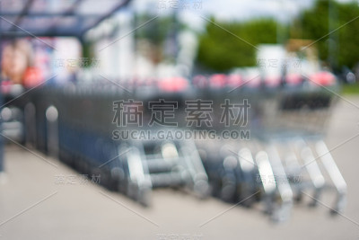 长方形玻璃屋顶下摆放着两排模糊的购物车。视图从后面。一切都模糊了。