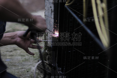 一个人用电焊机焊接金属来修理篱笆，焊工的职业，焊接金属，一个人用金属工作