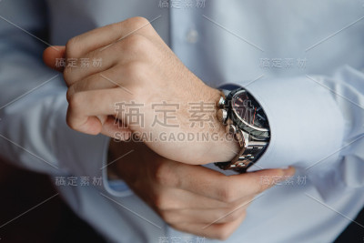 特写手新郎在蓝色衬衫与一个时钟