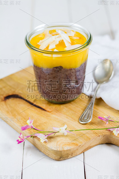 玻璃罐中有芒果和椰子片的黑米布丁。