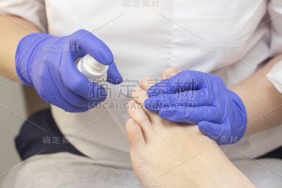 在美容院修脚。用抗菌剂进行足部消毒。美容师给一位女士的脚做足疗。