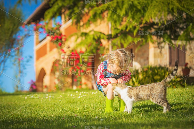 小女孩和小猫在绿色的草地上玩耍。