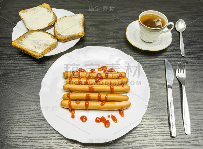 一盘加蕃茄酱的煮香肠，黑面包加黄油的三明治，还有袋子里的一杯泡好的茶。