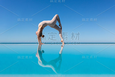 在泳池边做瑜伽的女人。