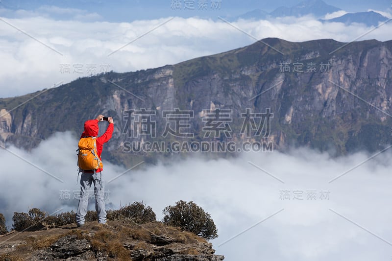 成功女背包客在山顶悬崖边自拍