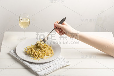 手握叉子，放意大利面和一杯白葡萄酒