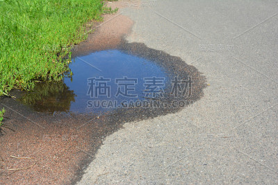 沥青路面上的水坑。破碎的沥青路面上的坑洞图像。