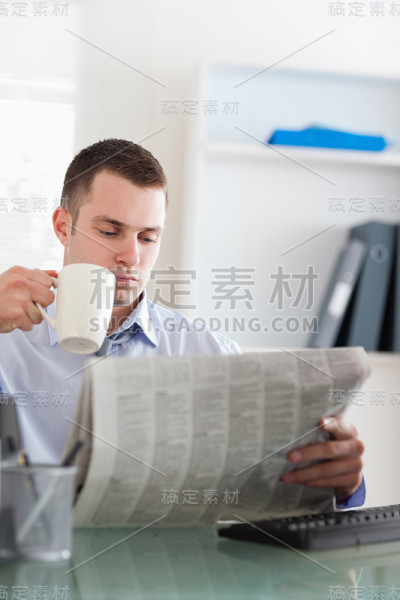 生意人一边看报纸一边喝咖啡