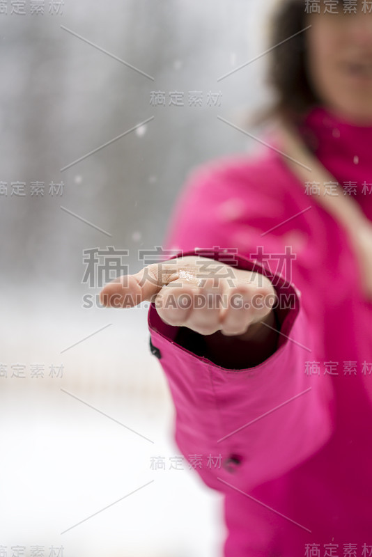 女性的手捕捉从天空飘落的雪花的特写