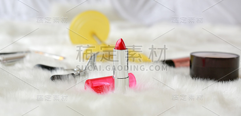 不同的化妆化妆品在白色人造毛皮的背景聚焦在口红，时尚的概念。