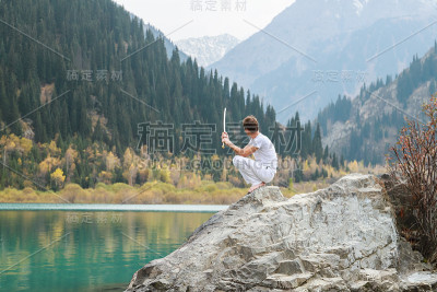 一个拿着剑的人坐在一块响亮的石头上。锋利的刀片。
