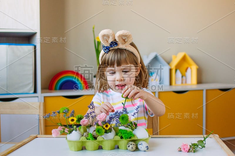 漂亮的小女孩用兔子耳朵做复活节装饰用鸡蛋和花