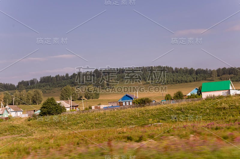 郊区和村庄。高山绿林。草地上的树木和它们的影子。夏天的一天，平静的深蓝色的天空和巨大的云周围。字段。