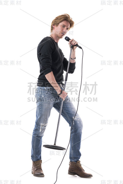 侧面的男子气概的摇滚音乐歌手唱歌在麦克风上的立场