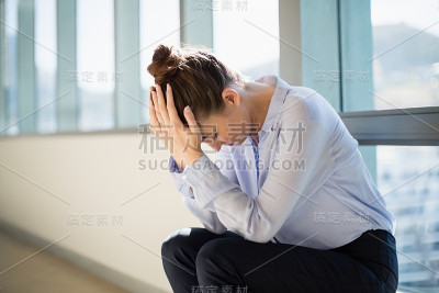 紧张的女性商务主管坐在那里，手放在额头上