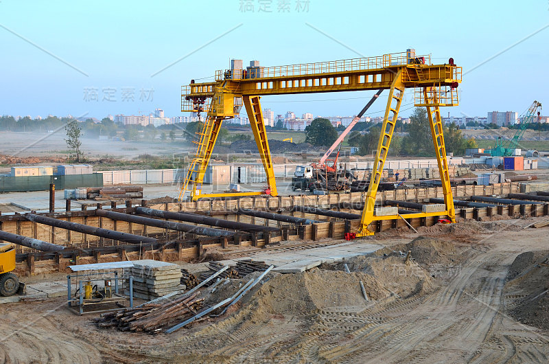 施工现场的门式起重机和汽车起重机。为修建地铁线路地下隧道而挖坑。地铁建设项目，明斯克，白俄罗斯，机场