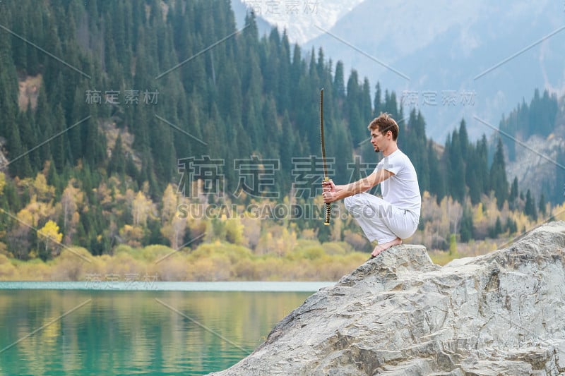 一个聪明人坐在石头上，手里拿着一把剑。山湖背景