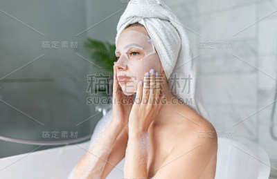 戴着面膜坐在浴缸里的女人