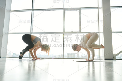 两个年轻活跃的妇女在运动服装站在手上练习瑜伽