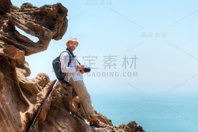 伊朗霍尔木兹岛，摄影师坐在一块岩石上旅行。