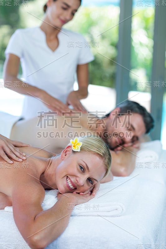 一对年轻夫妇接受按摩师的背部按摩