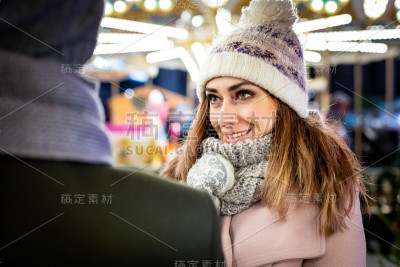 相爱的夫妇在晚上参观装饰过的圣诞市场