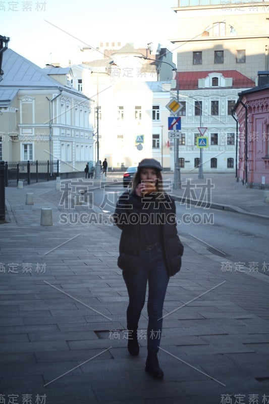 年轻漂亮的女孩在街上吃牛角面包